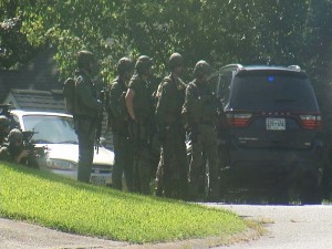 In this frame from video, law enforcement officers surround a house in Hixson, Tenn., Thursday, July 16, 2015. A gunman unleashed a barrage of fire at two sites a few miles apart in Chattanooga, killing several, officials said. The attacker was also killed. (AP Photo/Alex Sanz)