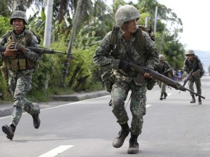 Philippine Marines cross an intersection to avoid a sniper fire during a standoff for the second day Tuesday Sept. 10, 2013 as about 200 Muslim rebels, enraged by a broken peace deal with the Philippine government, held scores of hostages as human shields at the southern port city of Zamboanga, in southern Philippines. More battle-ready troops and police were flown to the southern port city of Zamboanga in a bid to end the crisis. The troops have surrounded the Moro National Liberation Front guerrillas with their hostages in four coastal villages since the crisis erupted Monday. (AP Photo/Bullit Marquez)