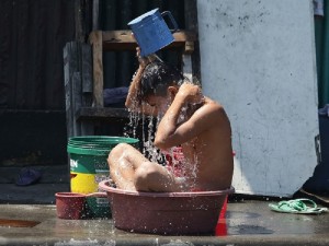 A Filipino boy sits inside a plastic container as he takes a bath to cool off himself at a Manila suburb, Philippines on Sunday, April 7, 2013. (AP Photo/Aaron Favila)