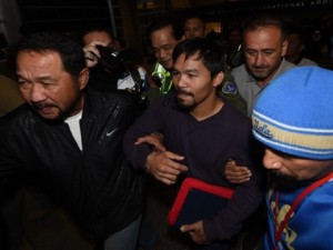 Filipino boxer Manny “Pacman” Pacquiao (C) is escorted by bodyguards as he arrives at Los Angeles International Airport to prepare for his upcoming fight against Timothy Bradley, in Los Angeles on March 12, 2016. Pacquiao will fight Bradley in Las Vegas on April 9th. / AFP / Mark Ralston