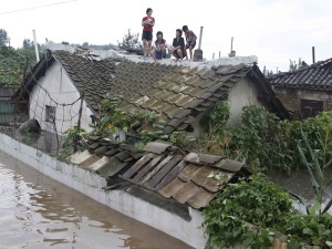 Residents wait on the roof of a flooded building in Anju City, South Phyongan Province, North Korea Monday, July 30, 2012. Officials said 1,000 houses and buildings were destroyed and 2,300 hectares of farmland were completely submerged in the city. (AP Photo/Kim Kwang Hyon)